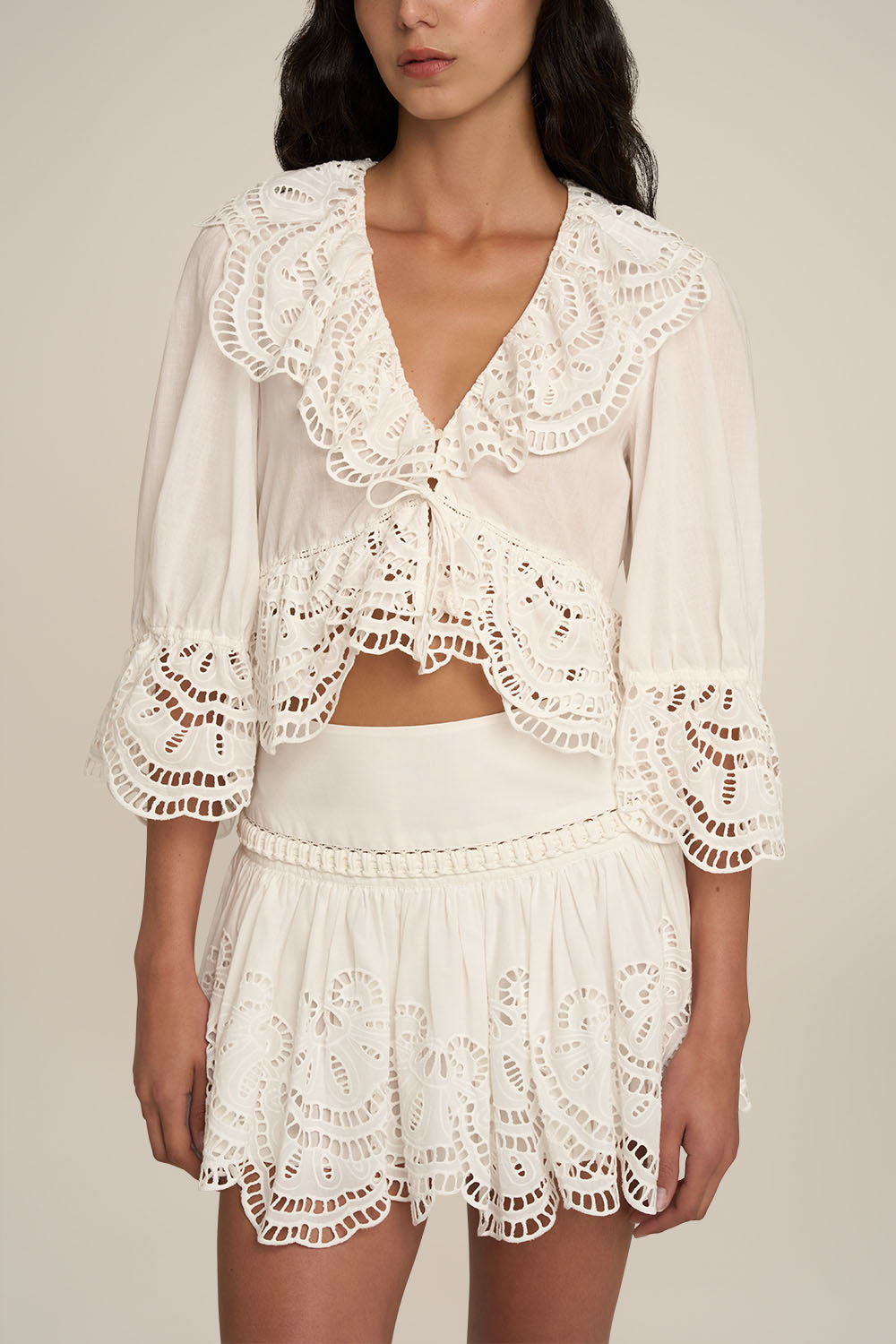 Poupette St Barth Blouse Casta in natural white, plain fabric, displayed with a miniskirt on a model in a stylish outdoor setting.