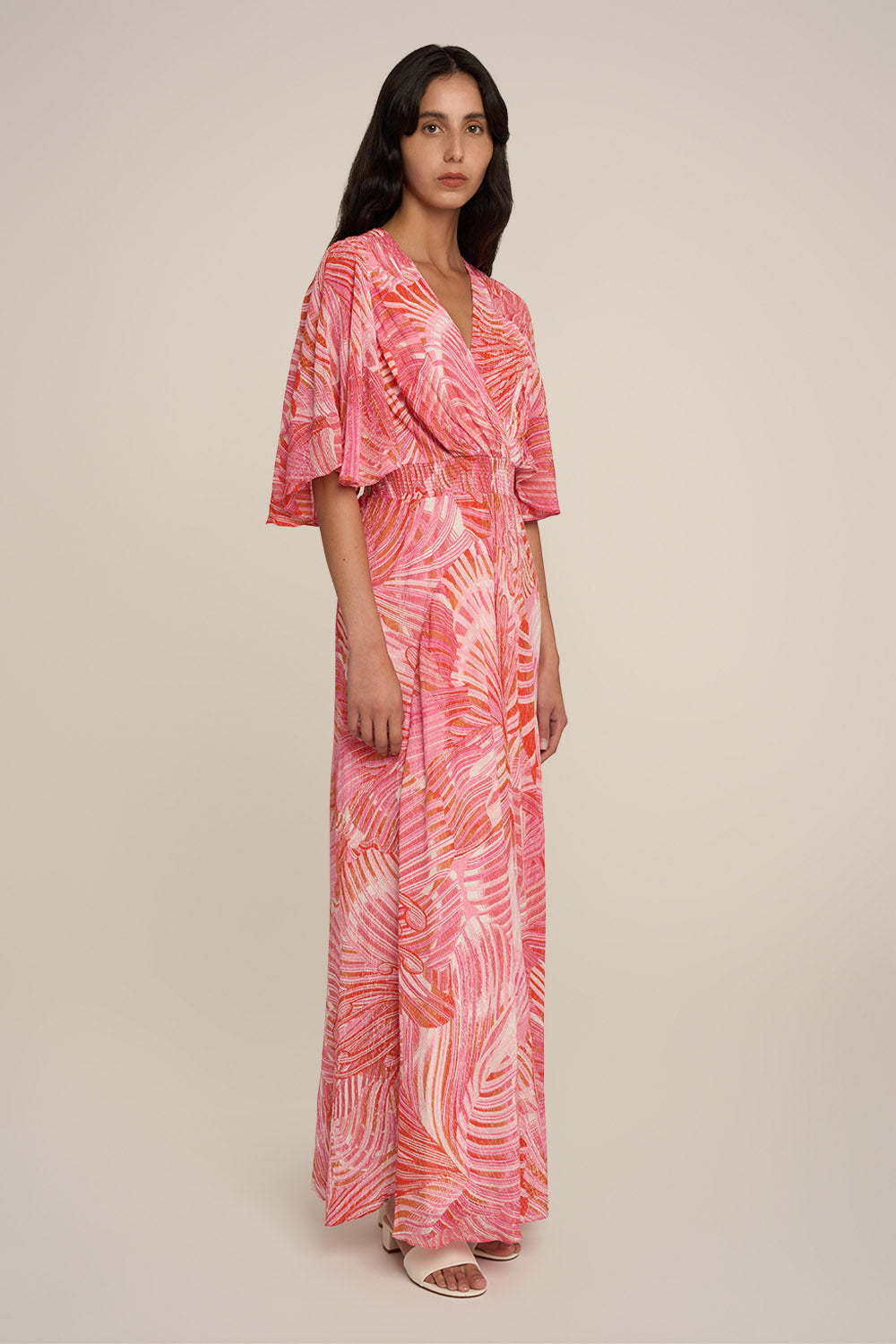 Pink long dress named Grace by Poupette St Barth, shown from the side with flowing fabric and elegant design details.
