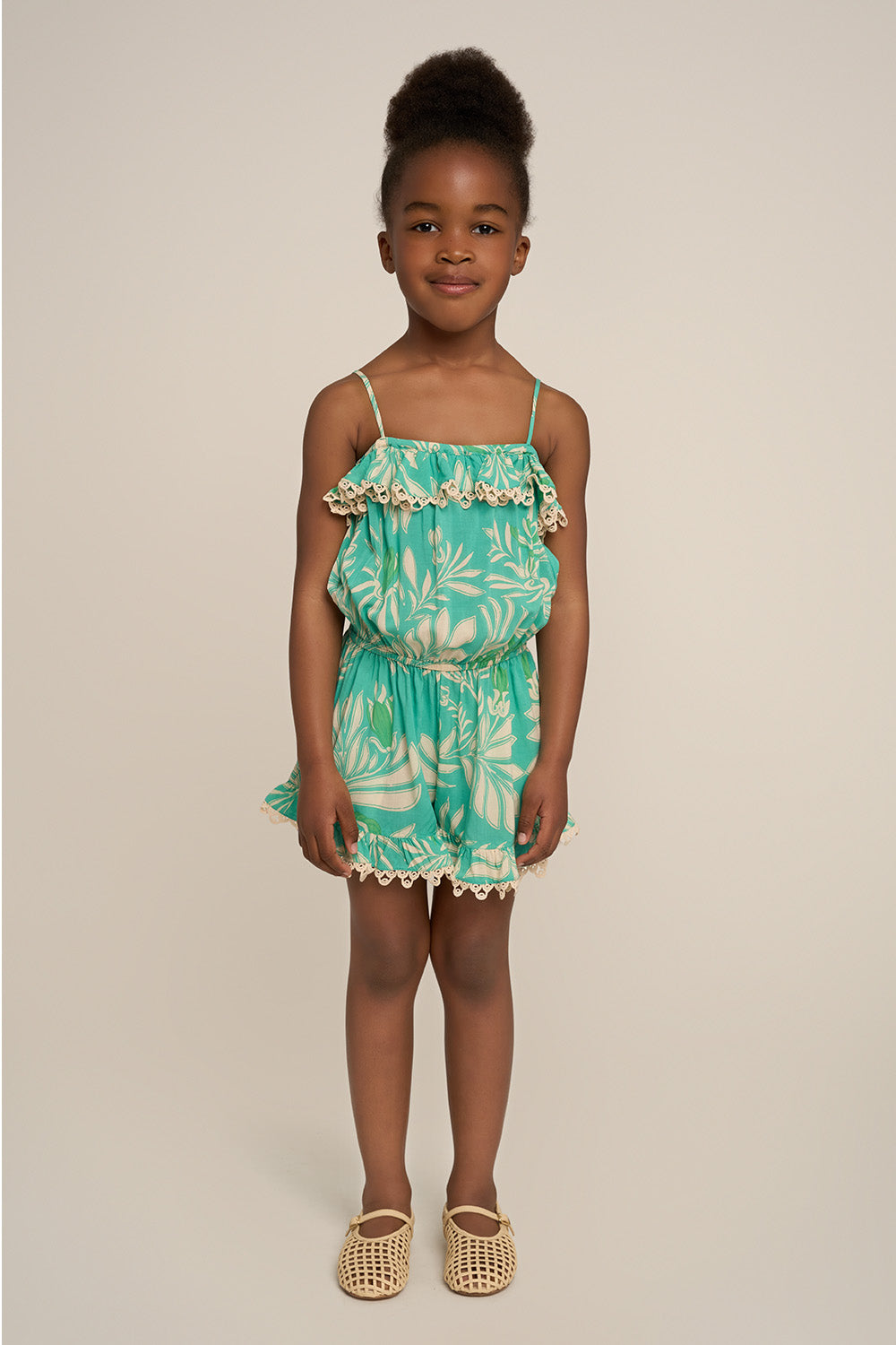 Girl wearing a blue short jumpsuit with angel print by Poupette St Barth, front view showing comfortable fit and playful design.
