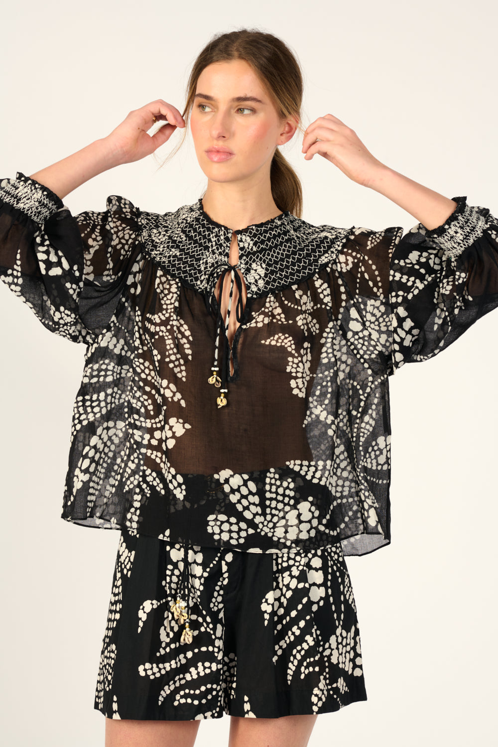 Black Ysee blouse by Poupette St Barth, featuring a short, flowy design with elegant detailing, displayed on a white background.