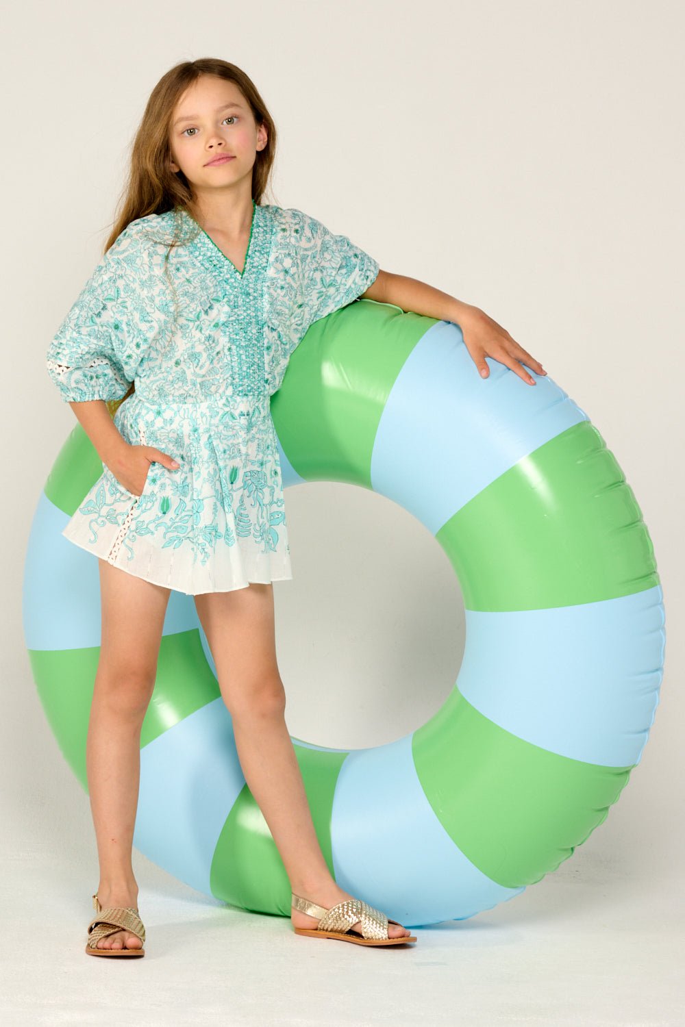 Girl wearing a bright aqua short jumpsuit by Poupette St Barth, featuring a comfortable fit and stylish design.