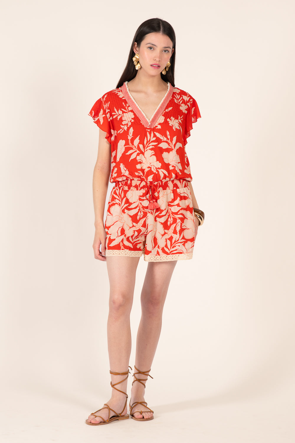 Coral short jumpsuit from Poupette St Barth's Sasha collection, featuring a stylish, lightweight design with tropical palm print.
