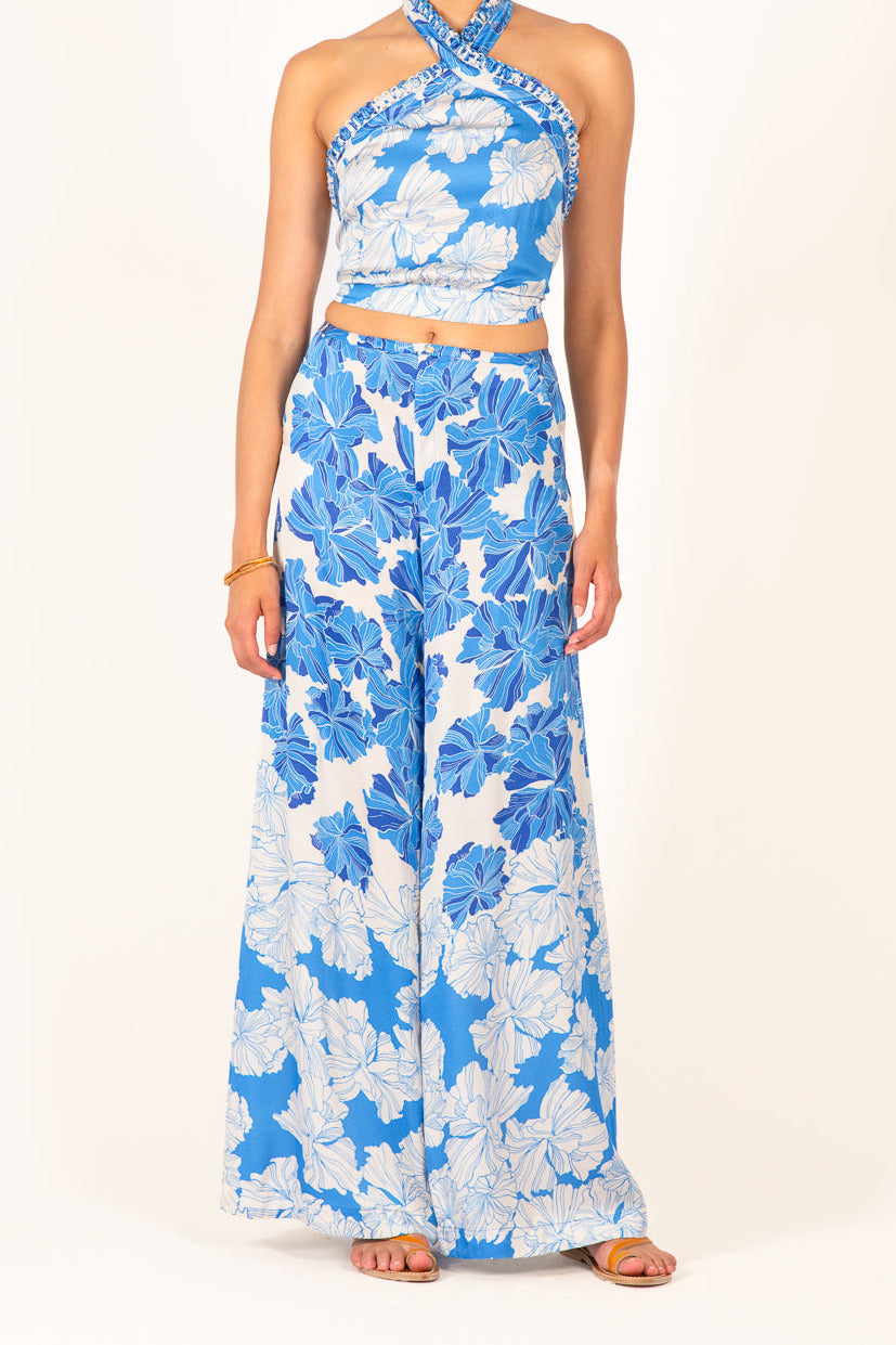 Blue floral print pants from Poupette St Barth's Pant Clea collection, made of silky viscose satin fabric with a vibrant flower design.