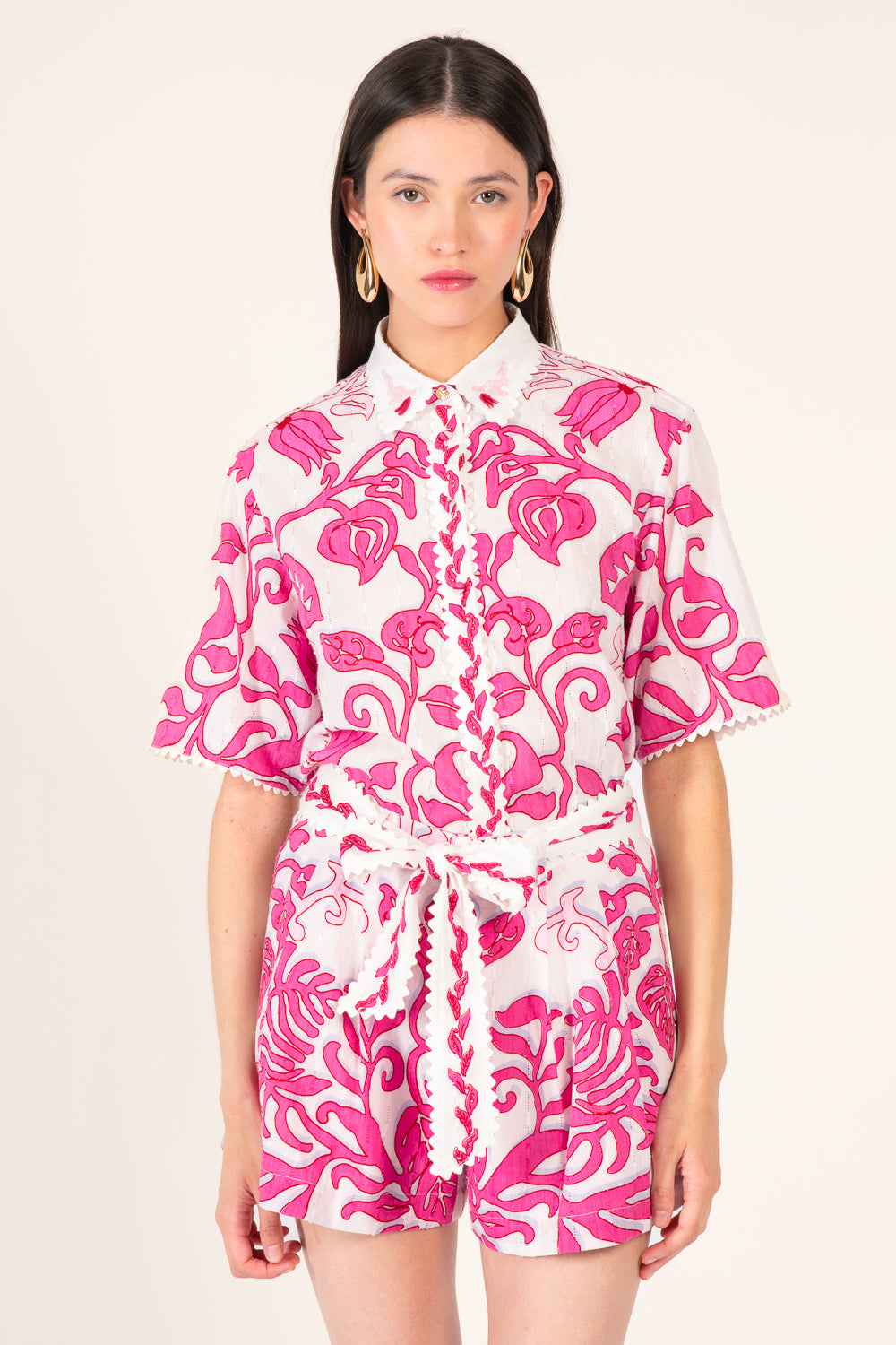White and pink Poupette St Barth Chantal shorts with a relaxed fit, shown in a casual outdoor setting.