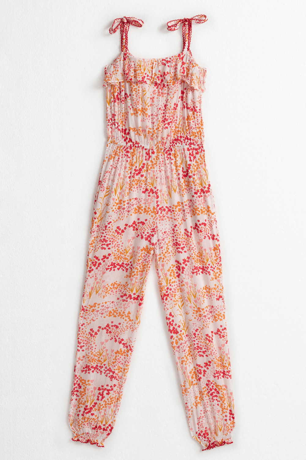 Back view of Poupette St Barth Kids Astra long jumpsuit in white with pink tulip pattern, featuring long sleeves and playful design.