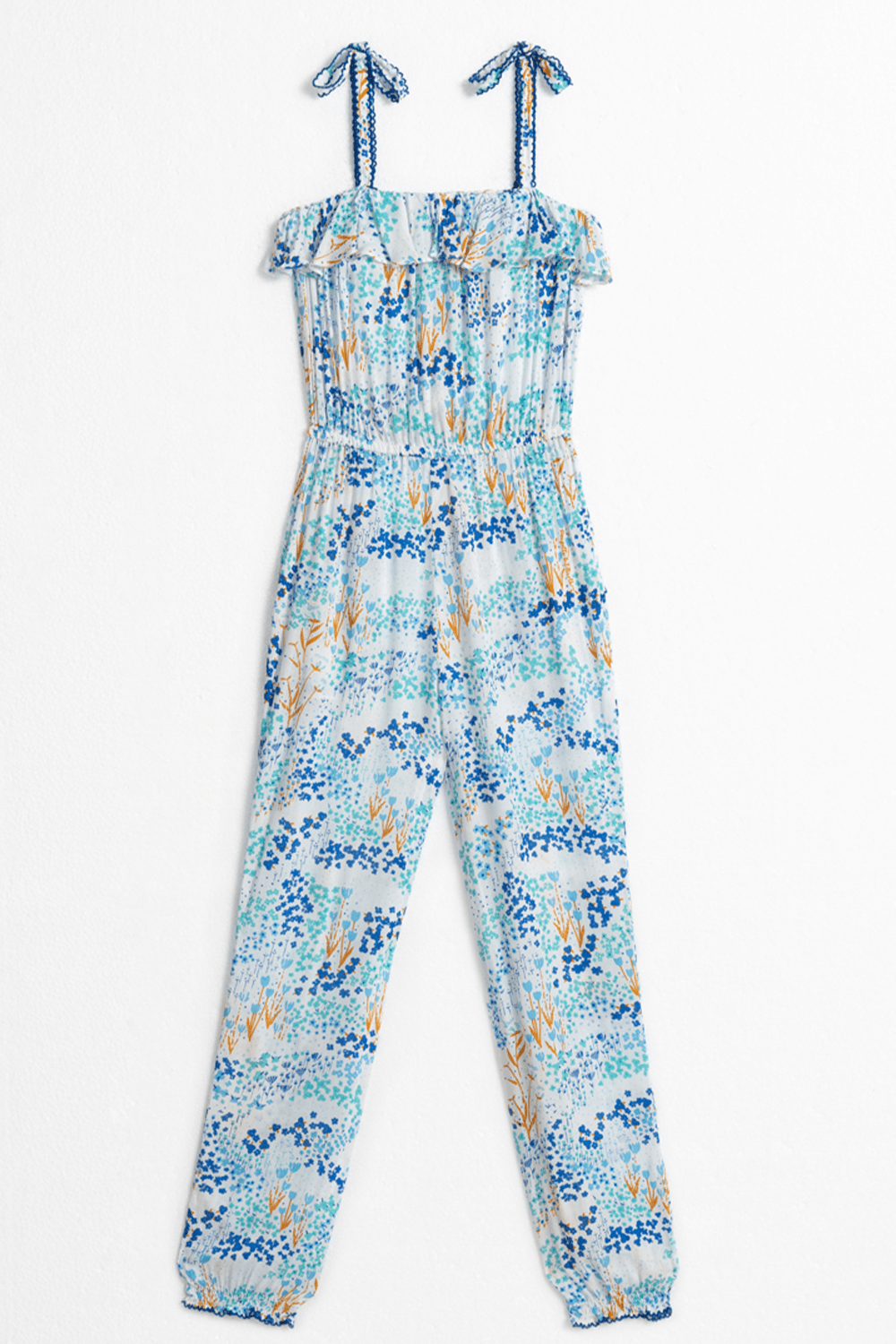 Back view of Poupette St Barth Kids Astra long jumpsuit in white and blue tulip print, featuring long sleeves and a relaxed fit.