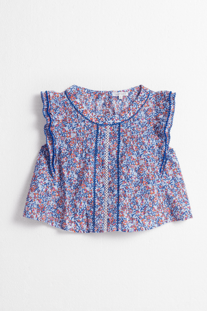 Light blue kids' top by Poupette St Barth featuring a playful paquerette pattern, front view of the shirt.